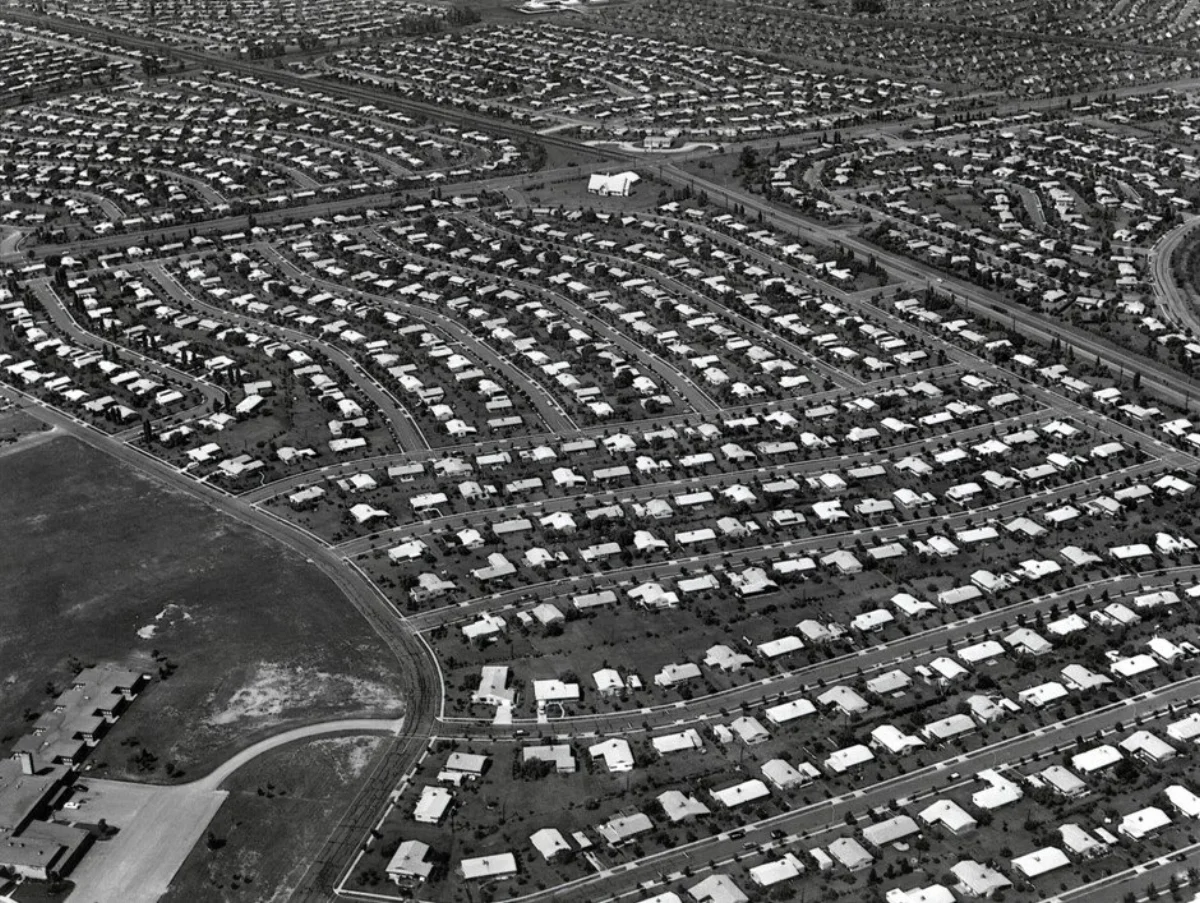 Black-and-white aerial photograph of Levittown, Pennsylvania showing hundreds of nearly identical small single-family tract houses laid out in curving rows across what was previously farmland