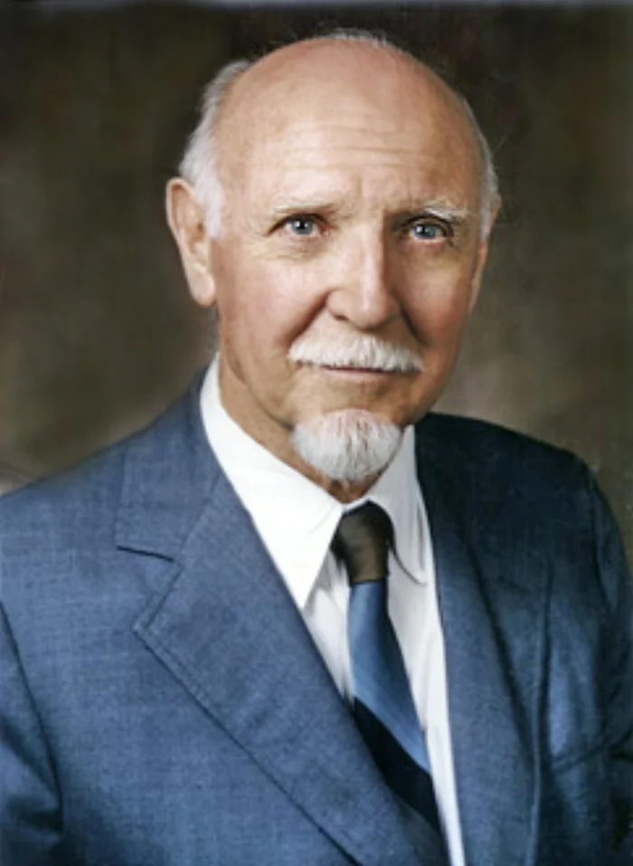 Color portrait of Raymond Cattell, an older man with a white goatee, wearing a blue suit and tie