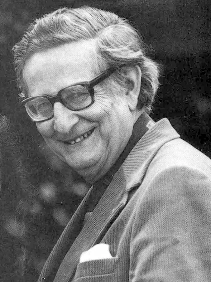 Black-and-white photograph of Hans Eysenck, an older man with glasses, smiling toward the camera in a tweed jacket