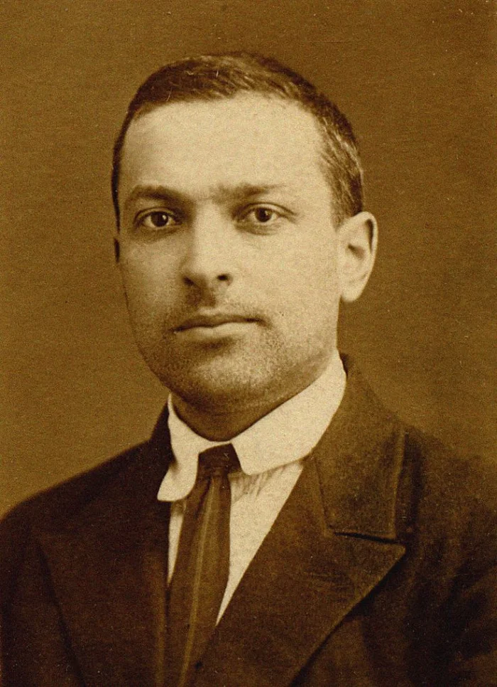 Sepia-toned formal portrait of a young Lev Vygotsky in a dark suit and tie, looking calmly at the camera