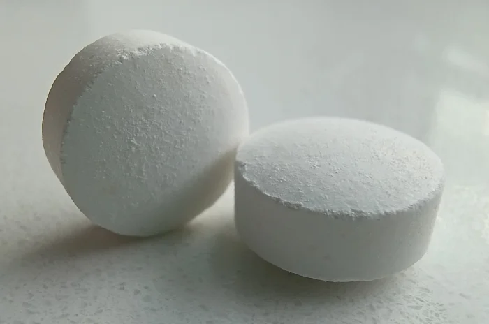 Two round, chalky white lithium salt tablets resting on a countertop