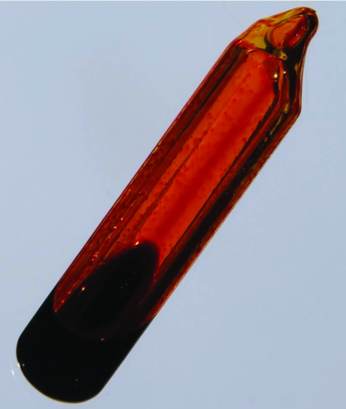 Photograph of a sealed glass tube containing liquid bromine at the bottom with reddish-brown bromine vapor above it, demonstrating a visible equilibrium between liquid and gas phases