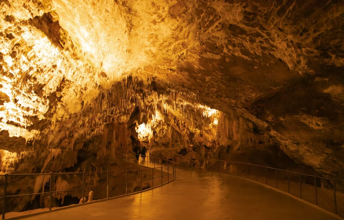Interior of a limestone cave with stalactites hanging from the ceiling and smooth walkways below, formed over thousands of years by the equilibrium between dissolved and solid calcium carbonate