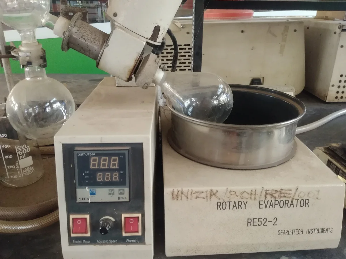 Rotary evaporator with rotating flask submerged in heated water bath and condenser to collect distilled solvent